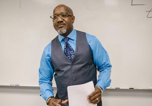 University instructor standing behind a desk